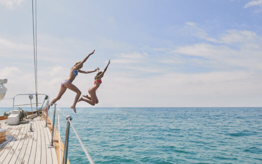 two-girls-jumping-off-boat-yacht-into-ocean-water-REASONS-TO-BUY-A-BOAT